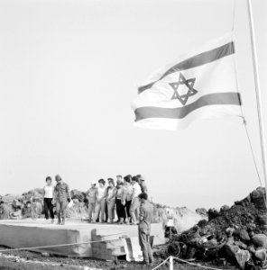 Groep jongeren staat op een podium onder de Israëlische vlag, twee van hen danse, Bestanddeelnr 255-3074
