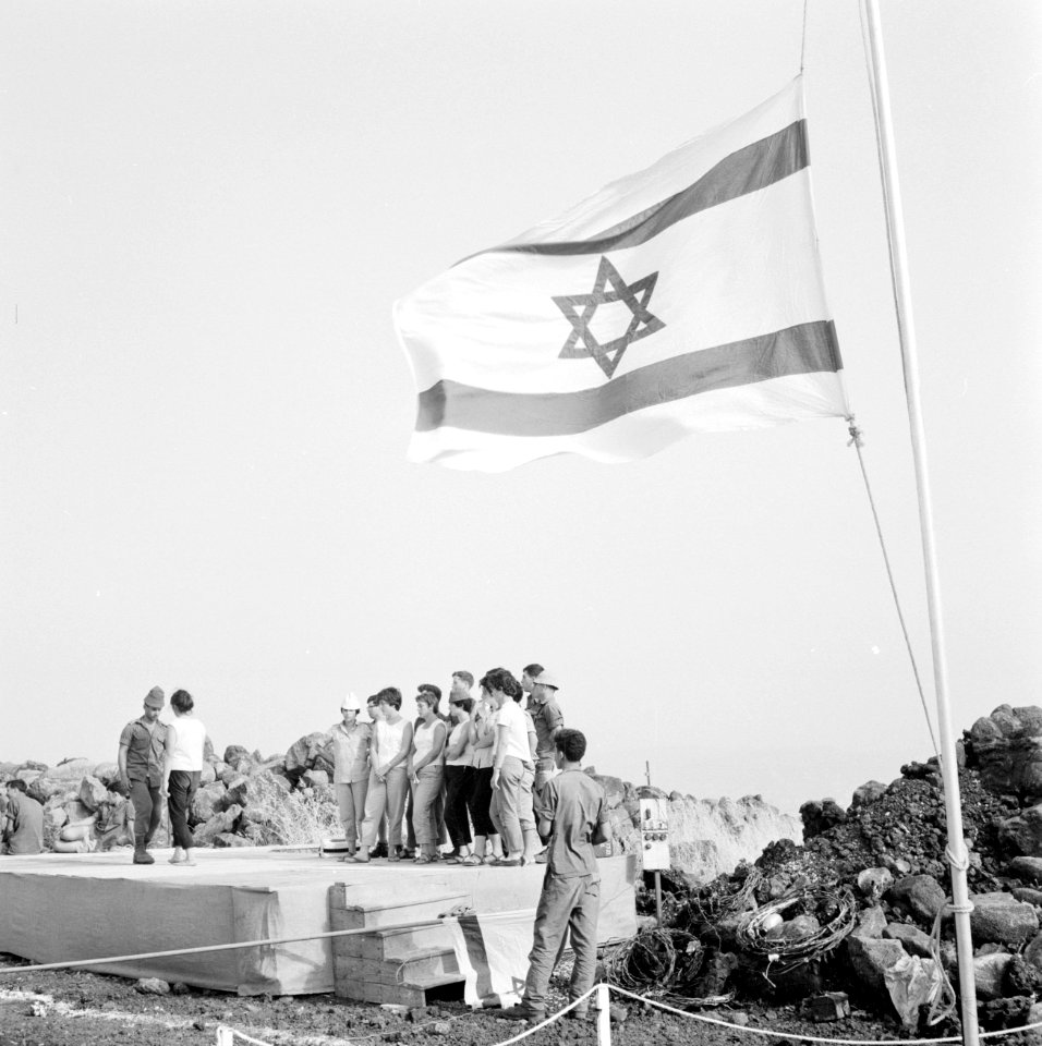 Groep jongeren staat op een podium onder de Israëlische vlag, twee van hen danse, Bestanddeelnr 255-3073