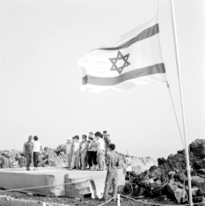 Groep jongeren staat op een podium onder de Israëlische vlag, twee van hen danse, Bestanddeelnr 255-3073