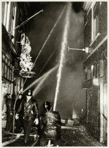 Het blussen van brand in de Paarlaarsteeg, bij de Koningstraat. Waar de draak buiten hangt, was het winkeltje in oosterse waren De Oriënt