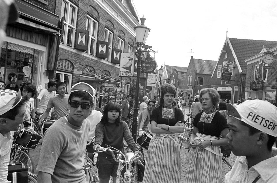 Groep Japanse fietsers in Volendam, met meisjes in Volendamse klederdracht, Bestanddeelnr 925-7973