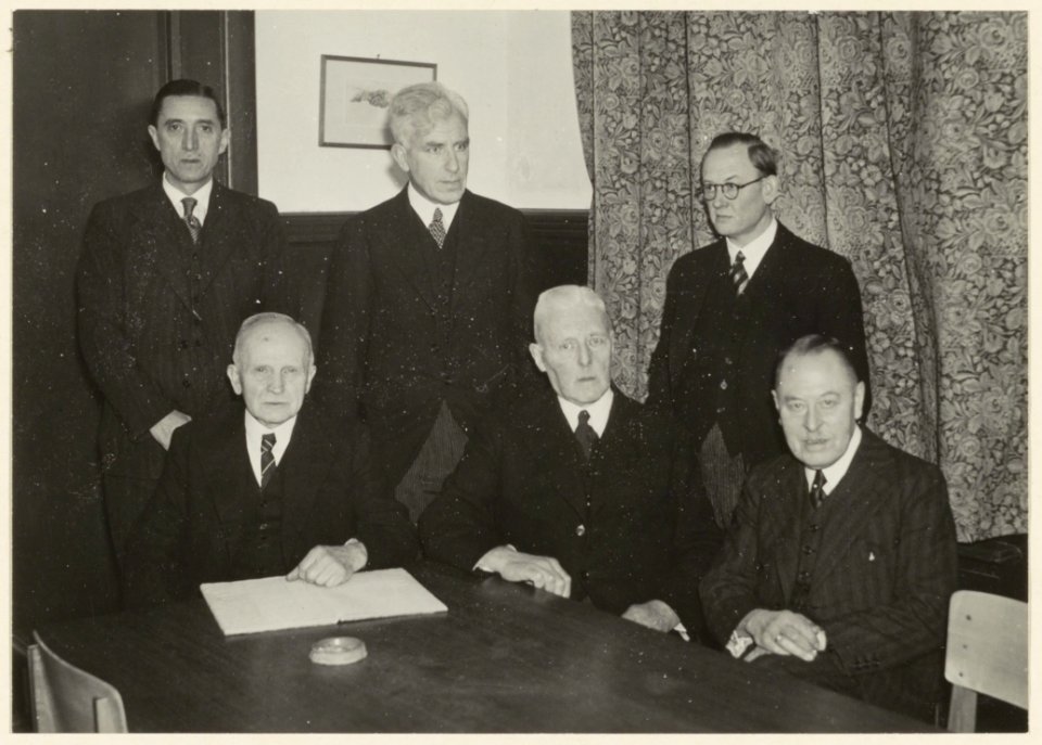 Het bestuur van de vereniging Weten en Werken tijdens de herdenking van het 90-jarig bestaan. Eerste rij v.l.n.r. secr.J.Ruinen, voorz.Dr.A.Land, penn.P.Hartogh Heys van Zoutveen. Tweede r, NL-HlmNHA 54004792