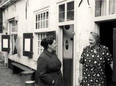 Het Brouwershofje of St. Maartenshofje, aan de Tuchthuisstraat nr. 8. De westzijde van het binnenterrein. Luus van Dusschoten (links) in gesprek met een van de bewoonsters. Aangekocht in 1977 van foto