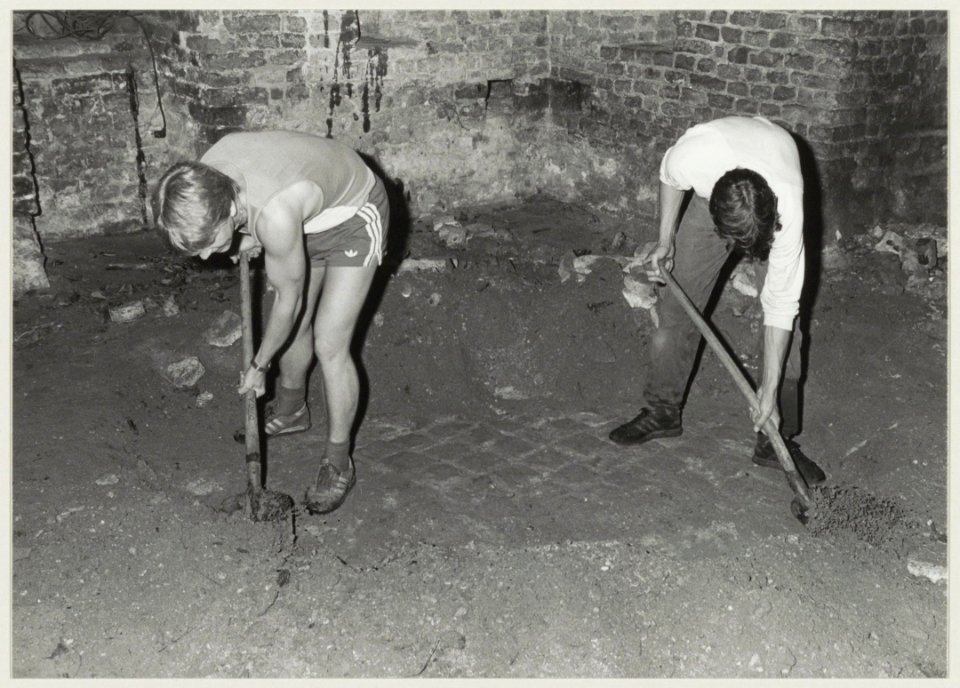 Het afpellen van een aardlaag, waaronder eeuwenlang een duurzame baksteenvloer verborgen heeft gelegen in de kapeltoren van de Ruïne van Brederode. NL-HlmNHA 54013846