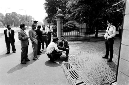 Herman Salassa zittend op een stoeltje voor de ingang van het Paleis, Bestanddeelnr 930-3507
