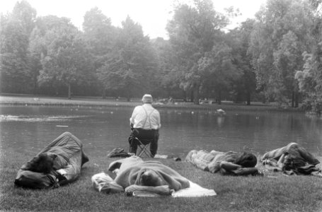 Hippies slapen in Vondelpark Amsterdam, man vist, terwijl jongeren slapen, Bestanddeelnr 924-7323