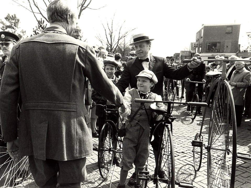 Historische wieleroptocht op de Bennebroekerlaan te Bennebroek burgemeester J.de Widt geeft een jonge wielrijder de hand afbeelding door Fotopersbureau C.de Boer. - Haarlem de Boer, ca.1980., NL-HlmNHA 54016679