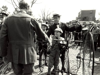 Historische wieleroptocht op de Bennebroekerlaan te Bennebroek burgemeester J.de Widt geeft een jonge wielrijder de hand afbeelding door Fotopersbureau C.de Boer. - Haarlem de Boer, ca.1980., NL-HlmNHA 54016679