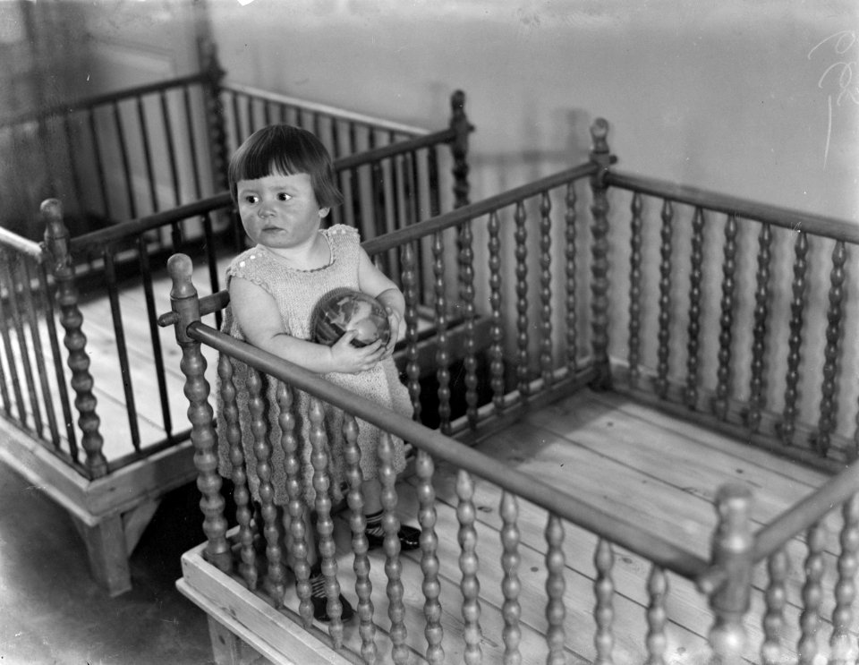 Het meisje Greetje in het Tehuis Annette staat in de box, Bestanddeelnr 252-0394