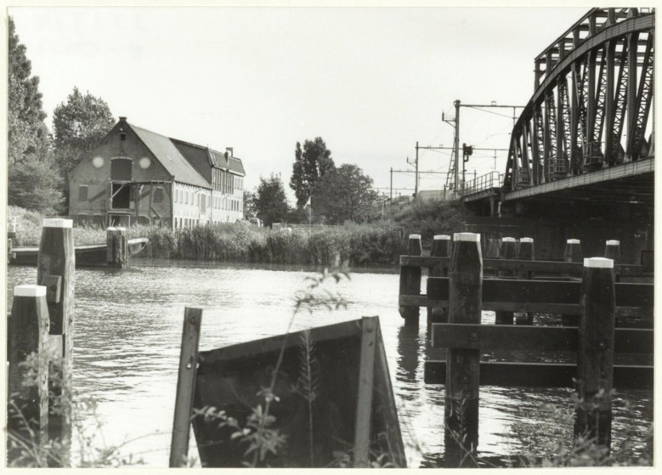 Het Noorder Buiten Spaarne met het gebouw van de voormalige drijfverenfabriek en de spoorbrug. NL-HlmNHA 54032149