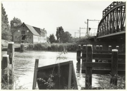 Het Noorder Buiten Spaarne met het gebouw van de voormalige drijfverenfabriek en de spoorbrug. NL-HlmNHA 54032149