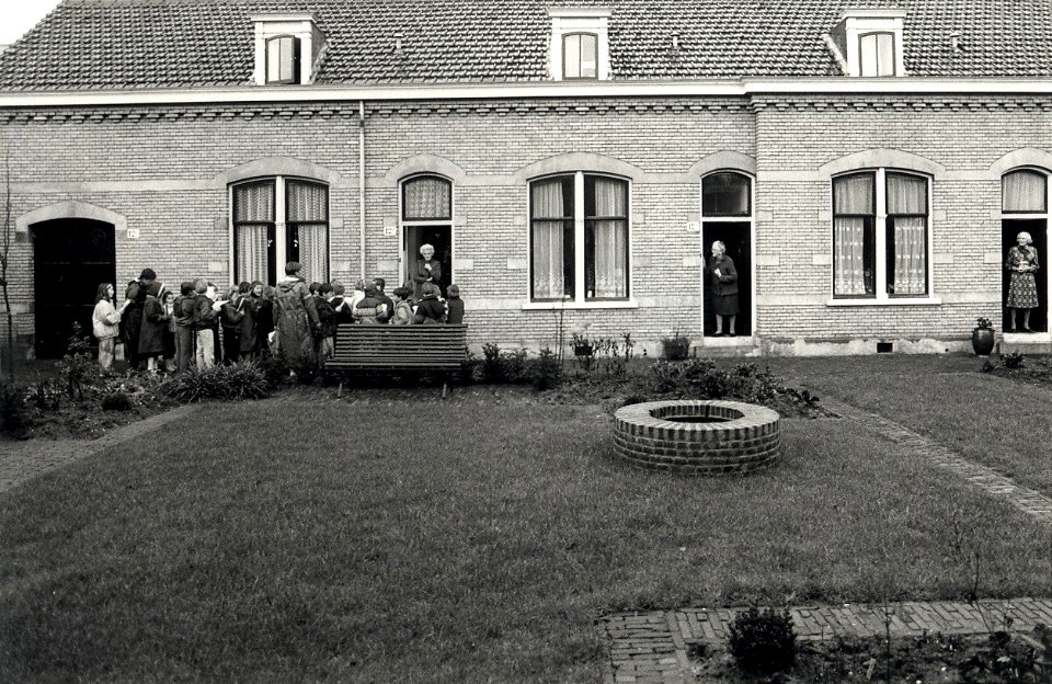Het Zuiderhofje aan de Zuiderstraat, scholieren van de Dreefschool brengen een kerstgroet. Aangekocht in 1987 van United Photos de Boer bv. - Negatiefnummer 25835 k 10 A. - Gepubliceerd in het Haarlem