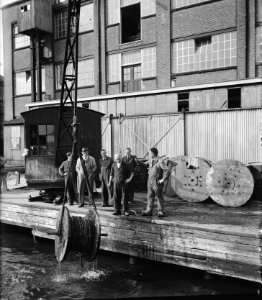 Het ophijsen van een ondergedoken kabelrol bij Draka fabrieken in Amsterdam, Bestanddeelnr 900-7703