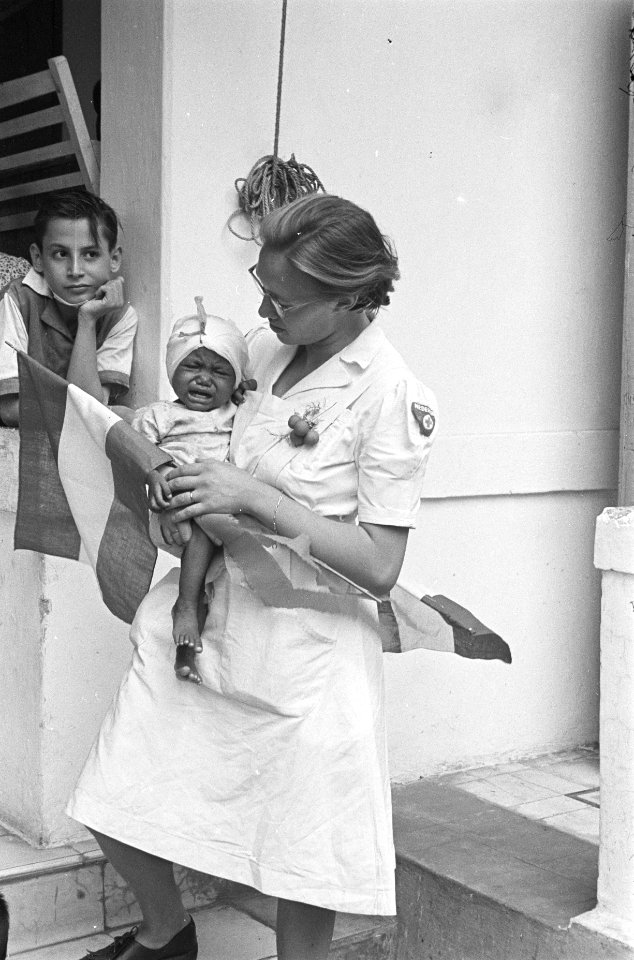 Het Prinses Margriet Hospitaal. Verpleegster en baby. Jongen kijkt toe, Bestanddeelnr 151-6-4