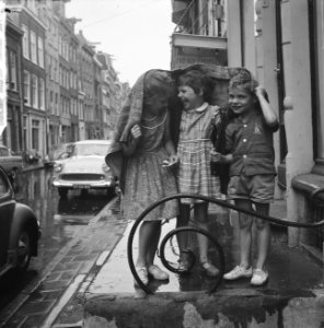 Hier en daar een buitje, kinderen schuilen voor de regen onder een tafelkleed, Bestanddeelnr 915-2309