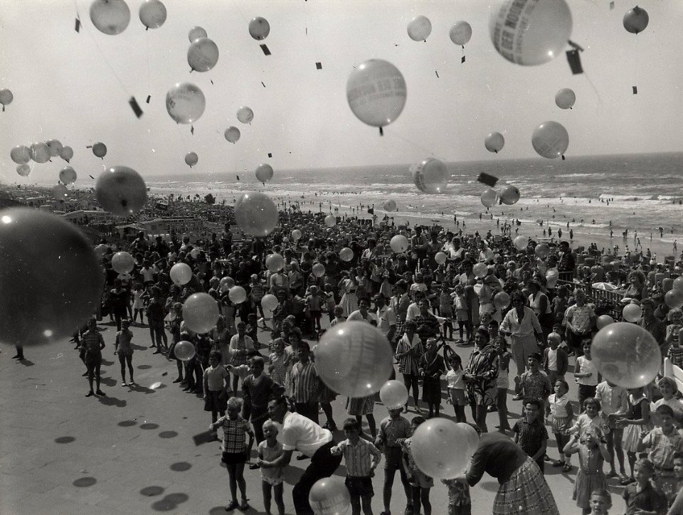 Het strand, voor de Rotonde, tijdens het oplaten van ballonnen met de opschrift 'Groeten uit Zandvoort'. Aangekocht in 1977 van fotograaf C. de Boer. Identificatienummer 54-004637, NL-HlmNHA 54004637