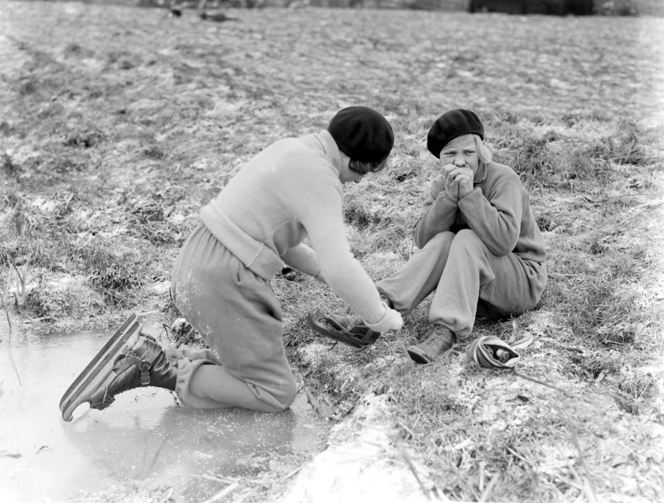 Hans helpt haar zus Renée met het onderbinden van de schaatsen al zittend op de , Bestanddeelnr 189-1044