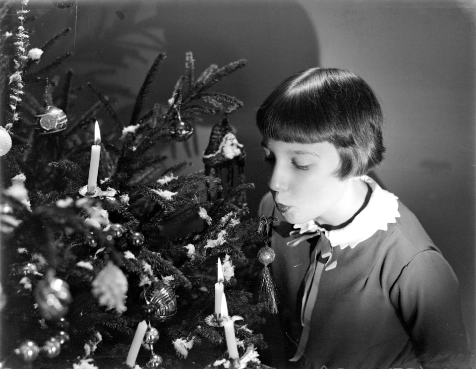 Hans (stiefdochter van Van de Poll) blaast een kaars uit in een Kerstboom, Bestanddeelnr 252-0961