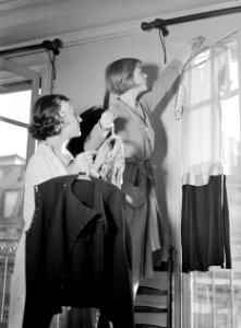 Hans geeft kleding aan en Renée hangt een jurkje voor het raam, Bestanddeelnr 255-8763