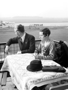 Harry Laponder met een onbekende vrouw op het terras van het luchthavengebouw me, Bestanddeelnr 190-1358