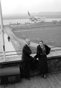 Harry Laponder met een onbekende vrouw op het terras van het luchthavengebouw me, Bestanddeelnr 190-1355