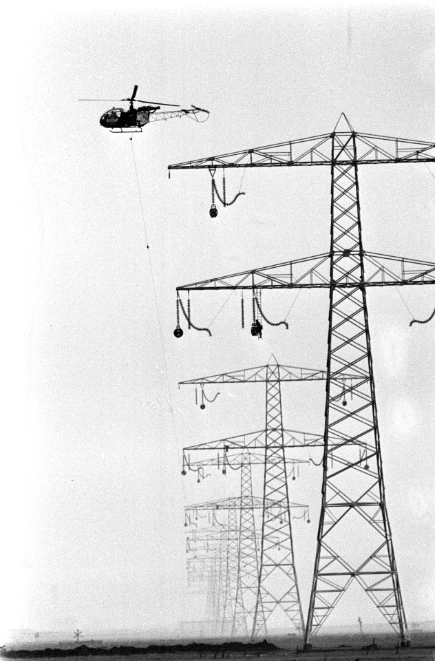 Helicopter met een leiding boven de hoogspanningsmasten, Bestanddeelnr 926-9889