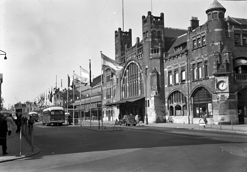 HUA-150363-Gezicht op het NS station Haarlem te Haarlem met vlaggen op het Stationsplein ter gelegenheid van de Floratentoonstelling
