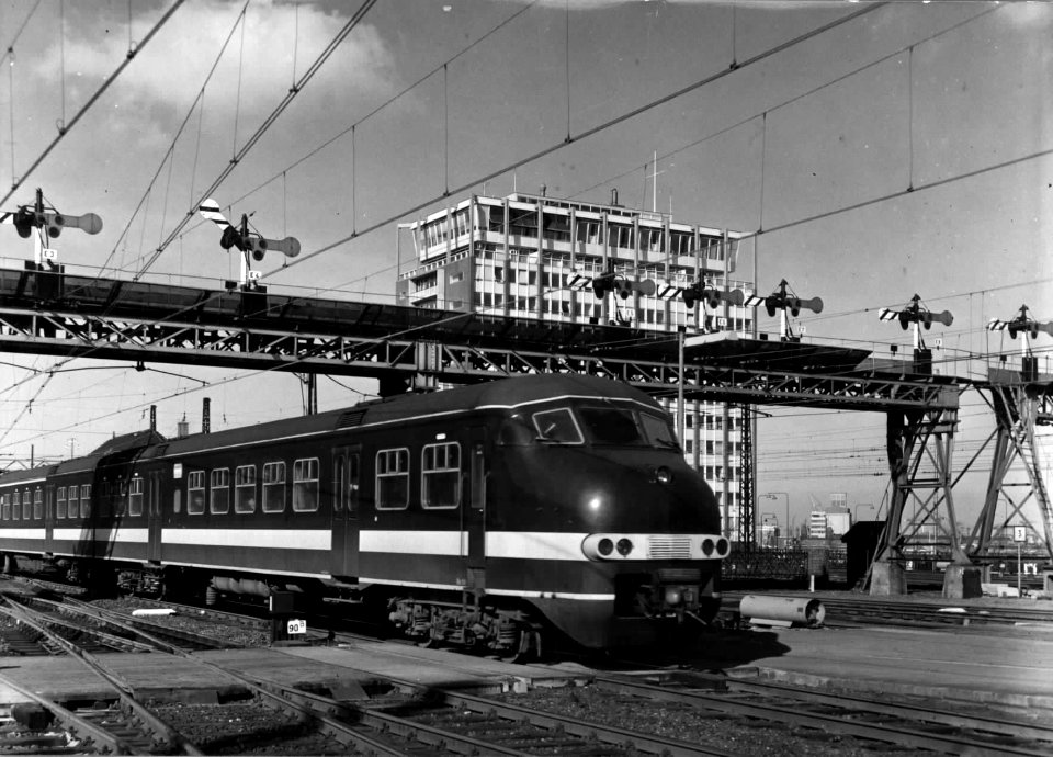 HUA-151873-Afbeelding van een electrisch treinstel mat. 1964 (plan T) van de N.S. onder de seinbrug van het N.S.-station Amsterdam C.S. (westzijde) te Amsterdam
