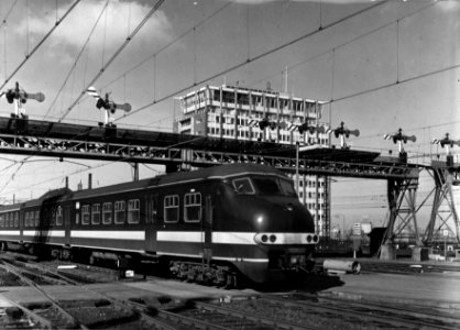 HUA-151873-Afbeelding van een electrisch treinstel mat. 1964 (plan T) van de N.S. onder de seinbrug van het N.S.-station Amsterdam C.S. (westzijde) te Amsterdam