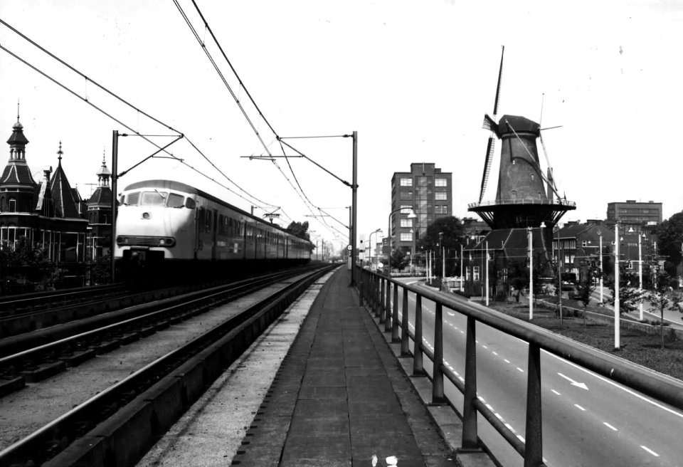 HUA-151896-Afbeelding van een electrisch treinstel mat 1964 plan T van de NS op het spoorviaduct te Delft met rechts de Phoenixstraat