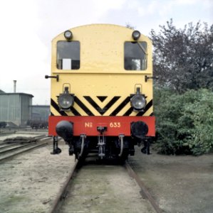 HUA-151541-Afbeelding van de diesel-electrische rangeerlocomotief nr. 633 (serie 600) van de N.S. in gele uitvoering en met schrikstrepen bij de hoofdwerkplaats van de N.S. te Tilburg