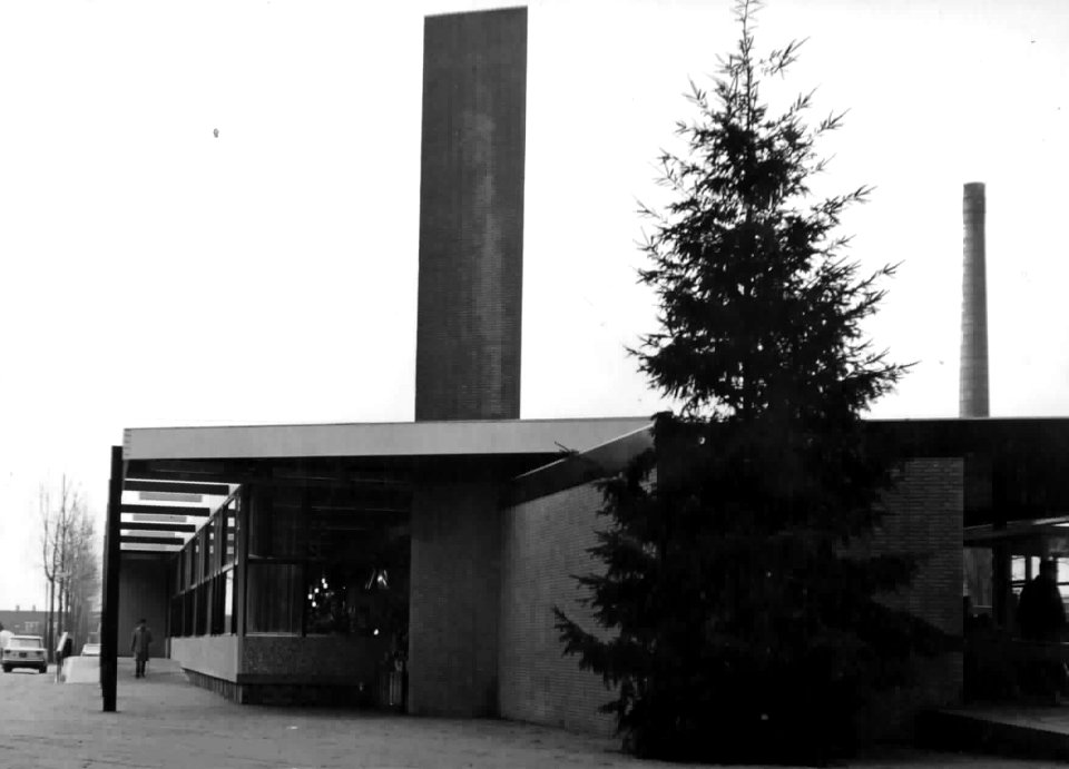HUA-150248-Gezicht op een zijgevel van het N.S.-station Driebergen-Zeist te Driebergen-Rijsenburg, met kerstboom en op de achtergrond de fabriekspijp van de Gevato