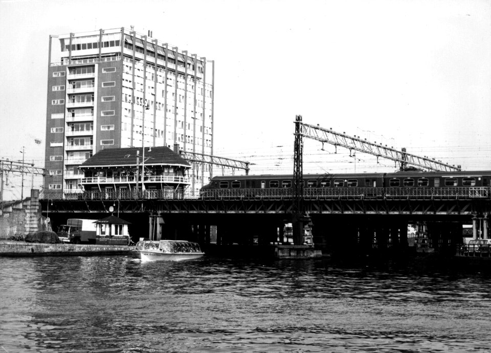 HUA-154922-Gezicht op de spoorbrug over de Westertoegang bij het NS station Amsterdam CS te Amsterdam Links het seinhuis met daarachter het Havengebouw