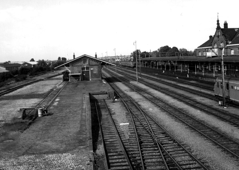HUA-154841-Gezicht op het emplacement van het N.S.-station Geldermalsen te Geldermalsen met het laadperron en de goederenloods en geheel rechts een deel van het stationsgebouw
