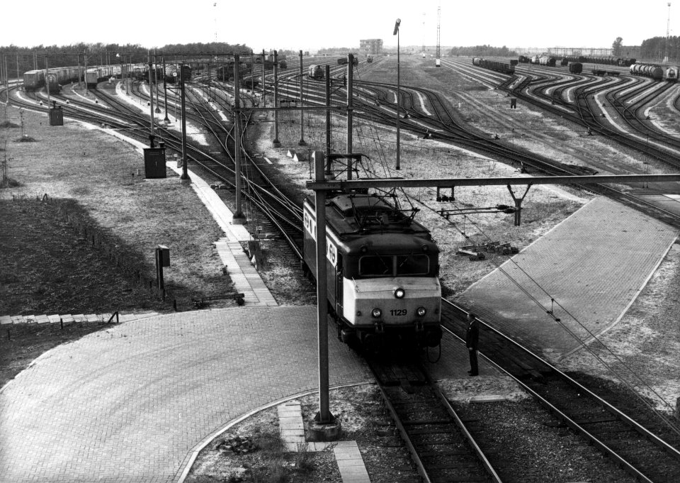 HUA-154869-Gezicht op het rangeerterrein Kijfhoek met vooraan de electrische locomotief nr. 1129 (serie 1100) van de N.S