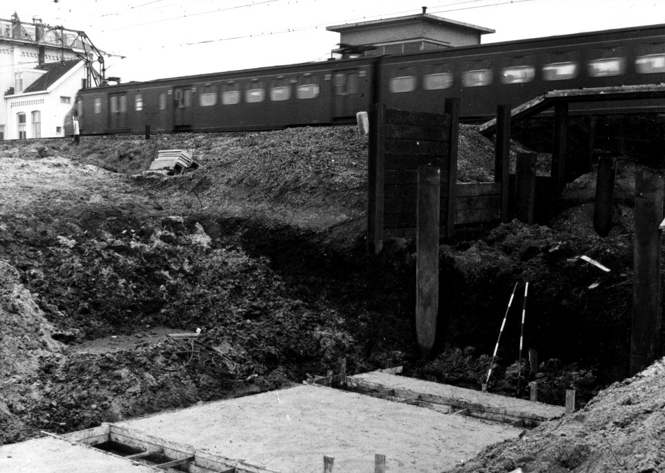 HUA-154875-Gezicht op de grondwerkzaamheden ten behoeve van de aanleg van het rangeerterrein Kijfhoek bij barendrecht met op de achtergrond een passerend electri