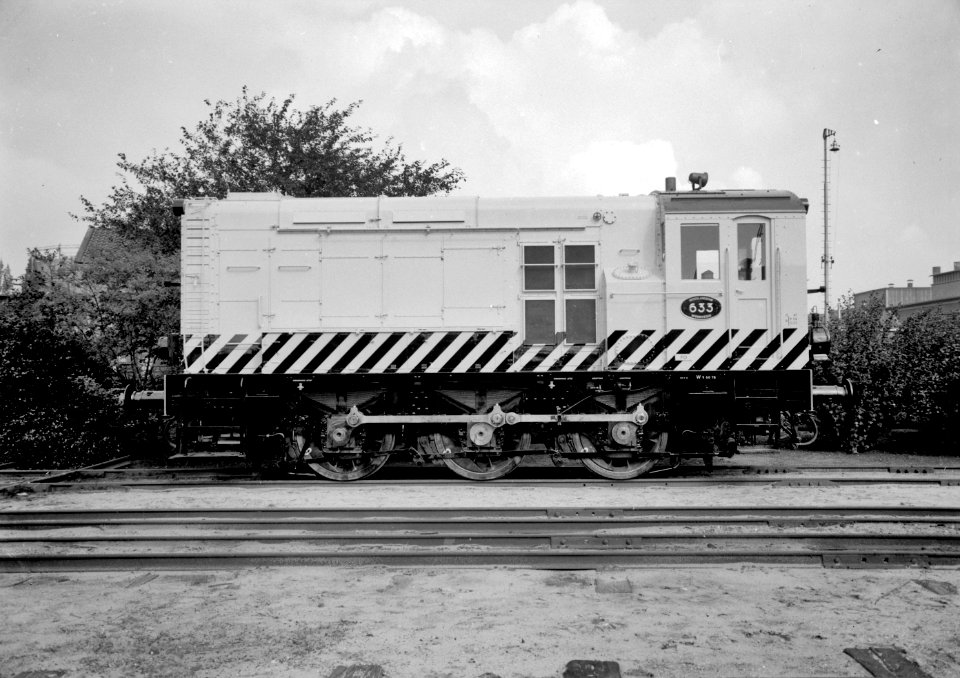 HUA-151545-Afbeelding van de diesel-electrische rangeerlocomotief nr. 633 (serie 600) van de N.S. in gele uitvoering en met schrikstrepen bij de hoofdwerkplaats van de N.S. te Tilburg