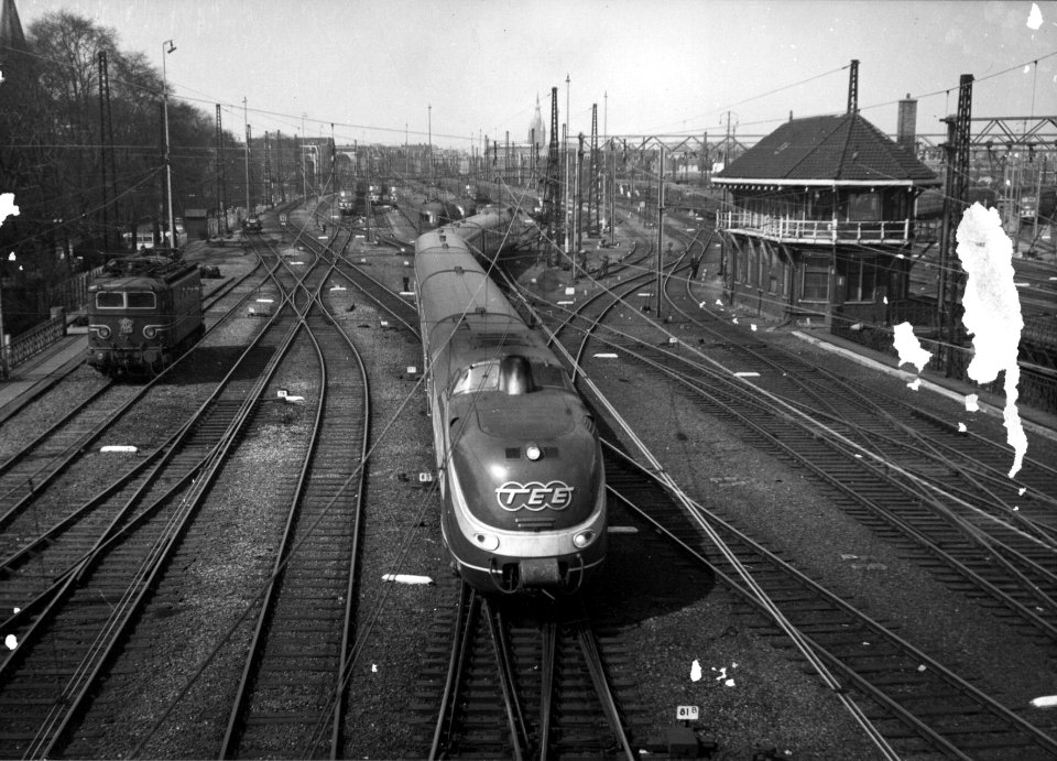 HUA-154814-Afbeelding van een TEE treinstel op het emplacement Westelijk Eiland van de NS te Amsterdam met rechts het seinhuis en links de electrische locomotief