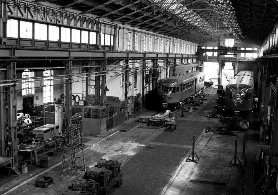 HUA-156540-Interieur van de hoofdwerkplaats van de N.S. te Haarlem met een diesel-electrisch motorrijtuig DE 1 en een diesel-electrisch treinstel DE 2 ("Blauwe Engel") van de N.S