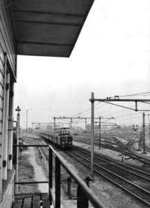HUA-154837-Gezicht vanuit het seinhuis Post T op de spoorlijn en het goederenstation te Elst en een electrische locomotief uit de serie 1100 van de N.S. met rijtuigen