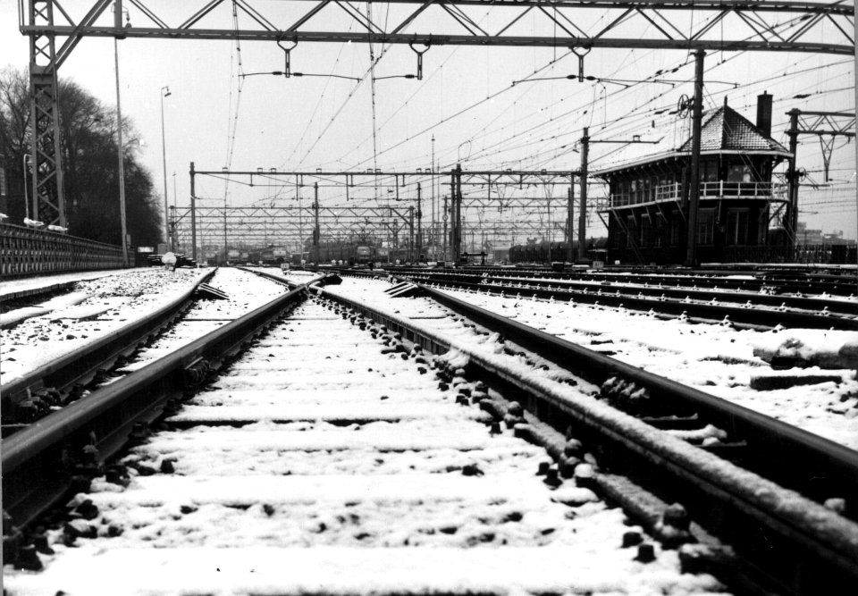 HUA-154826-Gezicht op het besneeuwde emplacement aan de westzijde van het N.S.-station Amsterdam C.S. te Amsterdam met rechts het seinhuis