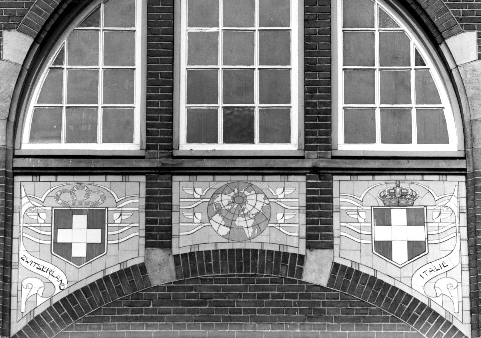 HUA-156157-Afbeelding van een tableau van sectieltegels aan de gevel van het N.S.-station Roosendaal te Roosendaal, voorstellende de wapenschilden van Zwitserland en Italië en een wereldbol