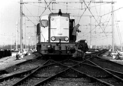 HUA-154896-Afbeelding van de rangerende diesel electrische locomotief nr 2441 serie 2400 2500 van de NS met twee rangeerders op het rangeerterrein Kijfhoek