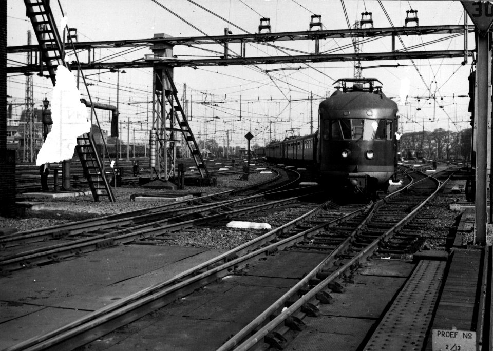 HUA-154791-Gezicht op het emplacement Dijksgracht te Amsterdam met een trein bestaande uit electrische treinstellen mat. 1946 van de N.S. N.B. De foto is links beschadigd