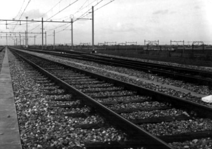 HUA-154850-Gezicht op het goederenemplacement van de NS te Heerjansdam met op de achtergrond de spoorlijn Rotterdam Dordrecht en een electrisch treinstel mat 196