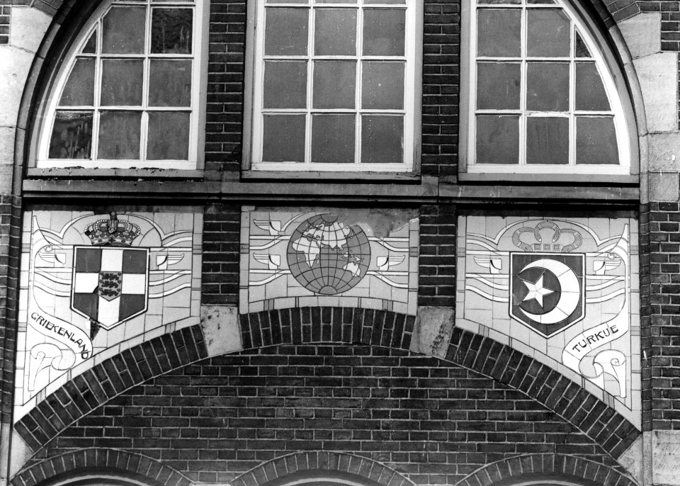 HUA-156154-Afbeelding van een tableau van sectieltegels aan de gevel van het N.S.-station Roosendaal te Roosendaal, voorstellende de wapenschilden van Griekenland en Turkije en een wereldbol