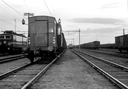 HUA-154778-Gezicht op het rangeerterrein van de NS te Amersfoort bij avond Links staat electrische locomotief nr 1153 serie 1100 van de NS