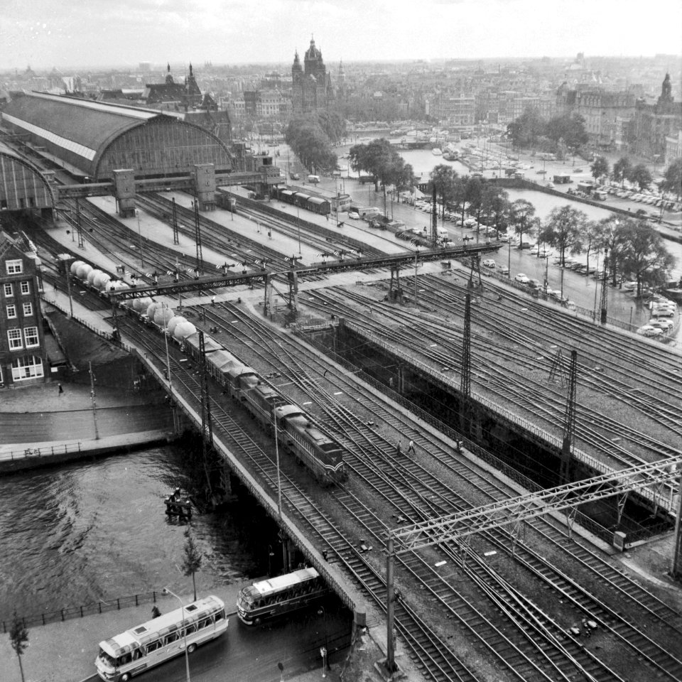 HUA-154800-Gezicht vanuit het havengebouw te Amsterdam op de westzijde van het NS station Amsterdam CS en de bruggen over de Westertoegang met een goederentrein 