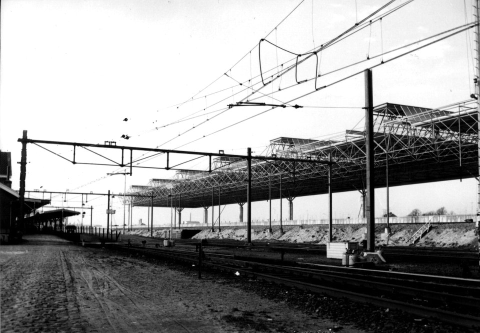 HUA-154403-Gezicht op de in aanbouw zijnde nieuwe perronkap van het N.S.-station Breda te Breda. Geheel links staat het oude stationsgebouw