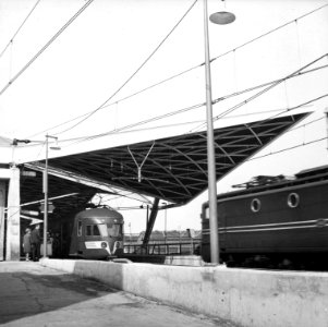 HUA-155026-Gezicht op de perronkap van het N.S.-station Tilburg te Tilburg met links langs het perron het electrische treinstel nr. 674 (mat. 1946) en rechts een passerende electrische locomotief uit de serie 13